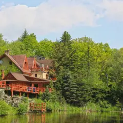 Drewniane domki i tarasy nad jeziorem w Miłoszycach, otoczone bujną zielenią drzew.