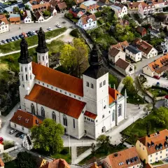 Widok z lotu ptaka na katedrę w Visby, otoczoną zabytkowymi budynkami z czerwonymi dachami.