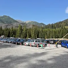 Duży parking na Łysej Polanie, pełen samochodów, z widokiem na góry i las.