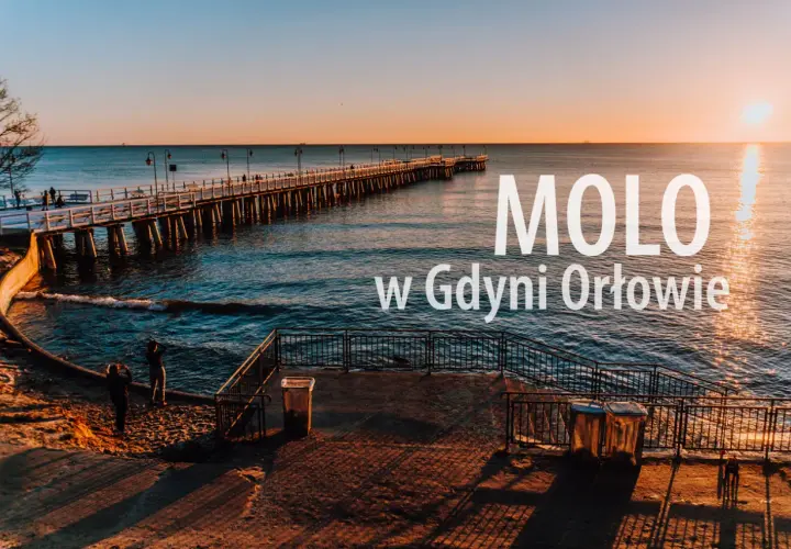 Zachód słońca nad morzem w dzielnicy Gdyni z molo. Długie molo w Orłowie, spokojne fale i dwie osoby na plaży.