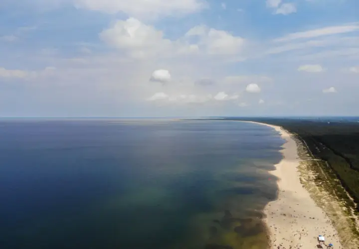 Szeroka, piaszczysta sobieszewo plaża z mnóstwem ludzi wypoczywających nad spokojnym morzem.