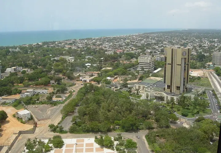 Widok na Lome, stolicę Togo, z dominującym złotym budynkiem i rozległym miastem w tle, nad którym rozciąga się ocean.