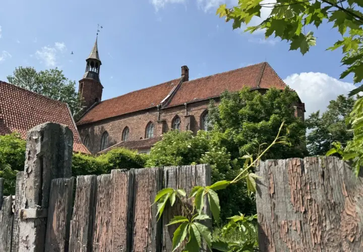 Stary, drewniany płot i ceglany kościół z wieżą w malowniczym mieście na Kociewiu.