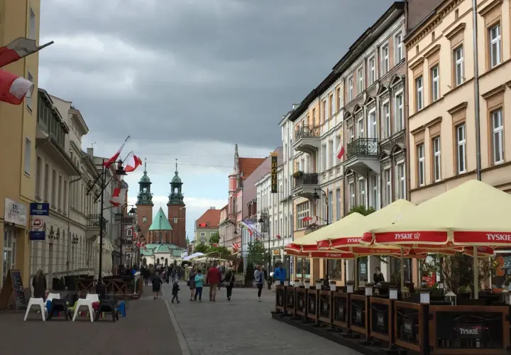 Spacer po Gnieźnie, gdzie widać zabytkowe kamienice, katedrę i ludzi odpoczywających w ogródku piwnym.