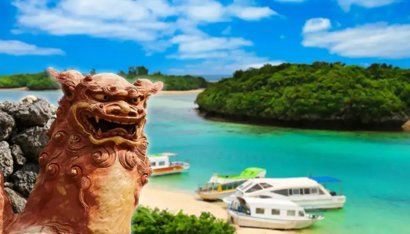 Kamienna lwica strzeże rajskiej plaży z łodziami na turkusowej wodzie. To piękny archipelag z Okinawą w tle.