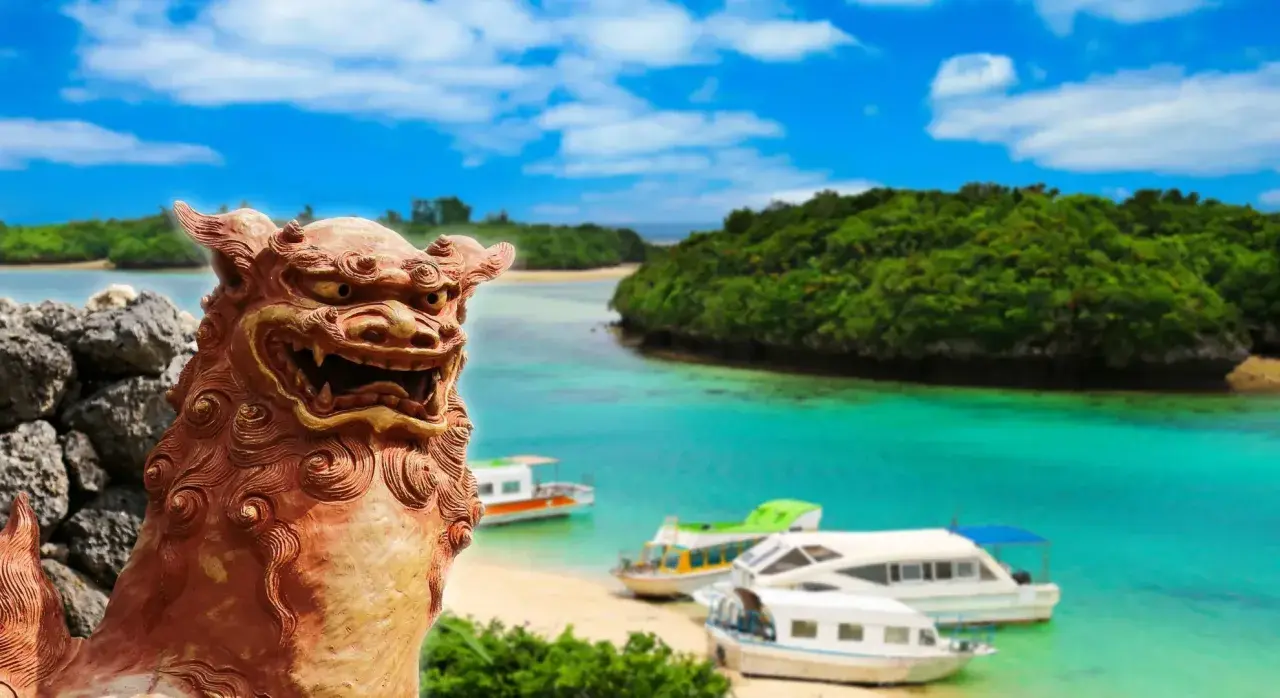 Kamienna lwica strzeże rajskiej plaży z łodziami na turkusowej wodzie. To piękny archipelag z Okinawą w tle.
