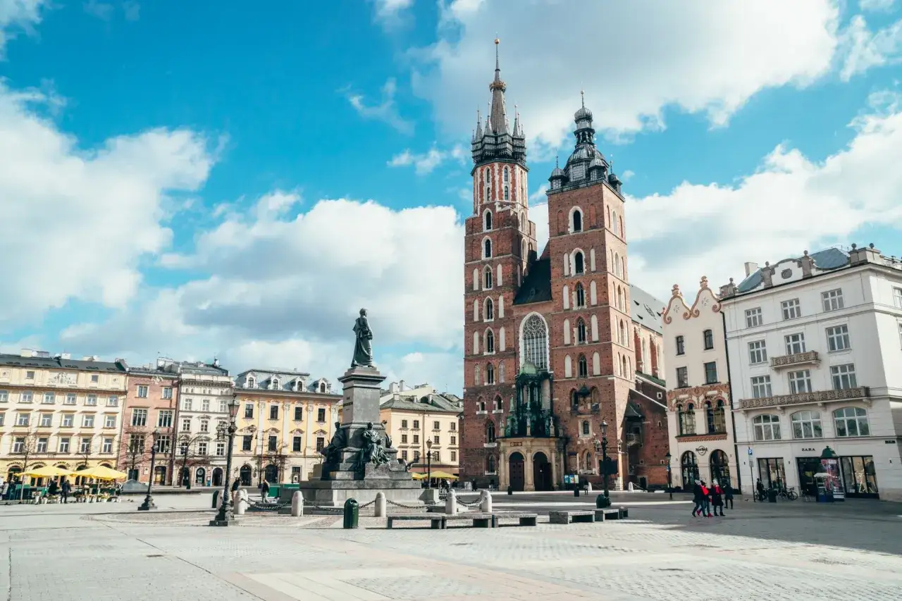 Rynek Główny Kraków: Bazylika Mariacka i Sukiennice pod błękitnym niebem.