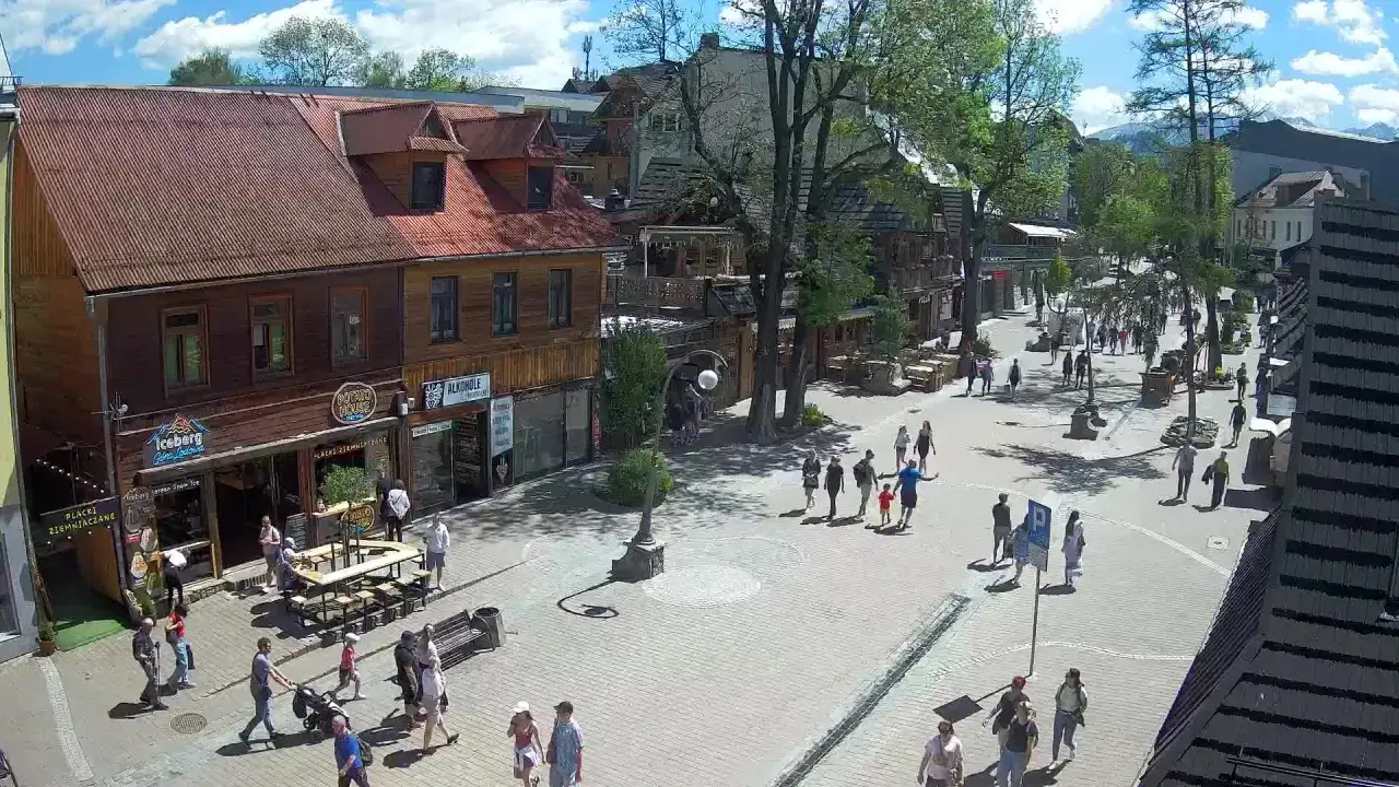 Spacer po tętniących życiem Krupówkach w Zakopanem. Ludzie spacerują, sklepy i restauracje zapraszają.
