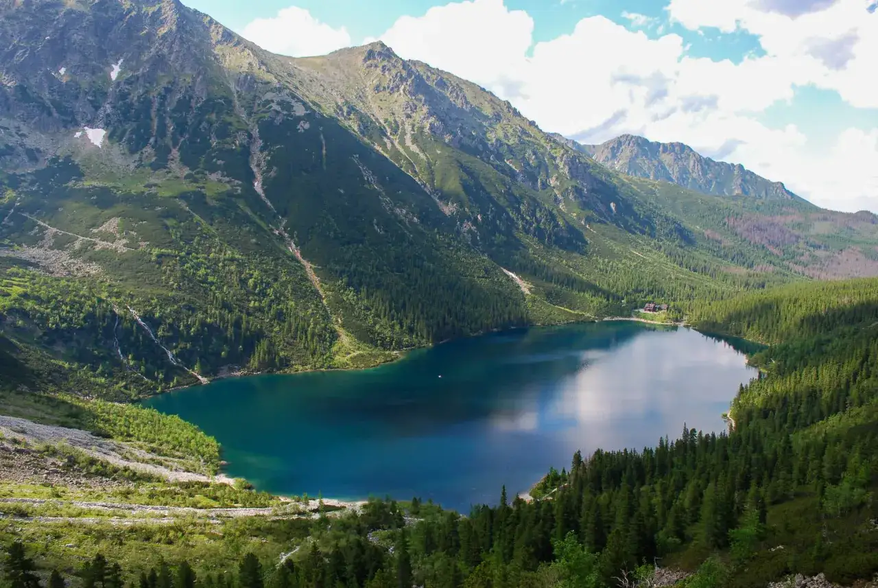 Malowniczy widok na Morskie Oko, z trasą wijącą się wśród zielonych zboczy i skalistych szczytów Tatr.